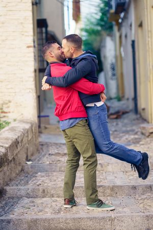 Male holding up his male partner in cute moment in narrow Spanish street