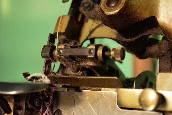 Fabric strip in tailor's bronze sewing machine with green background