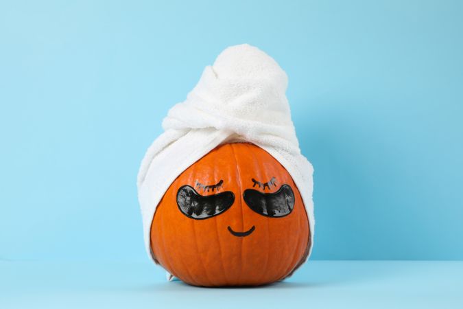 Pumpkin with towel and under eye patches against blue background
