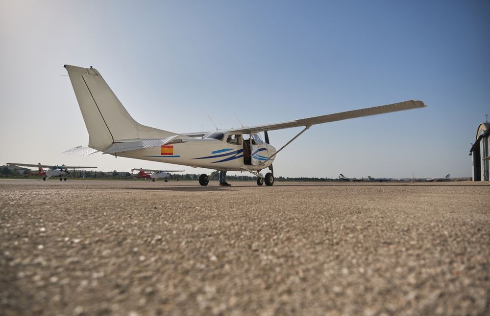 High wing aircraft parked on runway under blue sky