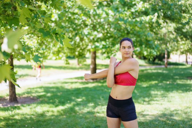 A woman practices stretching exercises in a sunny park, symbolizing fitness and wellness concepts on a summer day