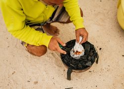 Tanned man cooking on camping stove beside parked mini van