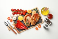 Board with fried steaks and ingredients for cooking on blank background, top view