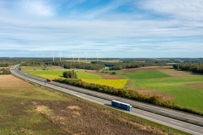 Highway and wind turbines in nature, drone aerial view in autumn