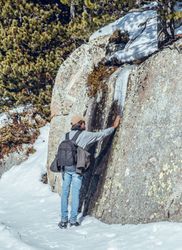 Man touching stone near trees in winter