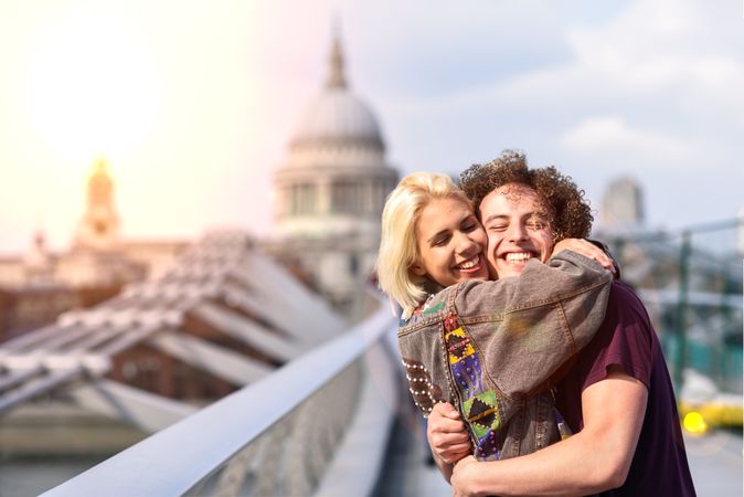 Man and woman smiling and hugging on bridge in London