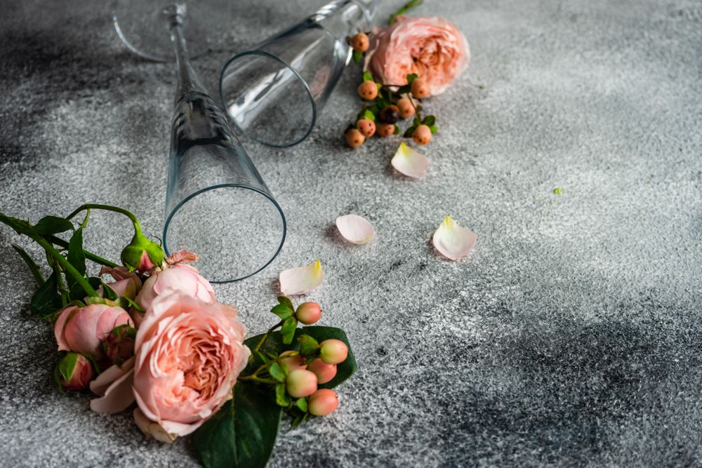 Pink flowers on grey background with champagne flutes