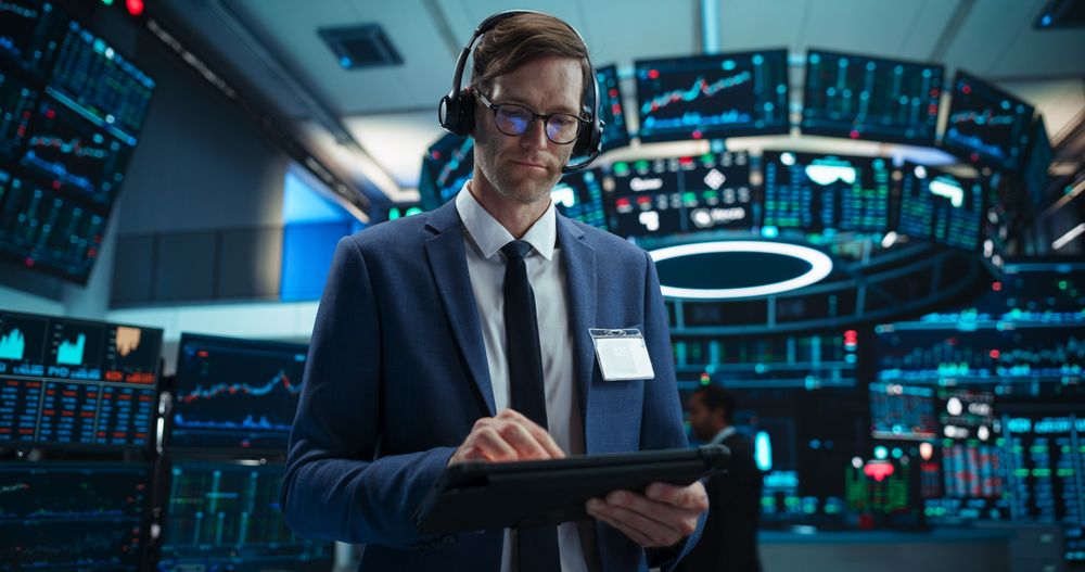 Portrait of a Stock Exchange Broker Using Tablet Computer, Researching Real-Time Stocks Data, Analyzing Commodities and Exchange Market Charts.