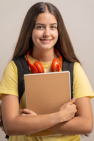 Portrait of a smiling young student holding a notebook, ready for school.