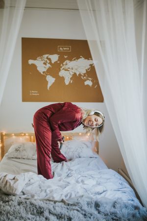 Woman with headphones dancing in bed