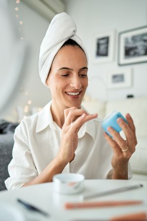 Positive female applying cream at home