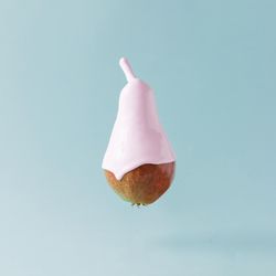 Pear with pink syrup on pastel blue background