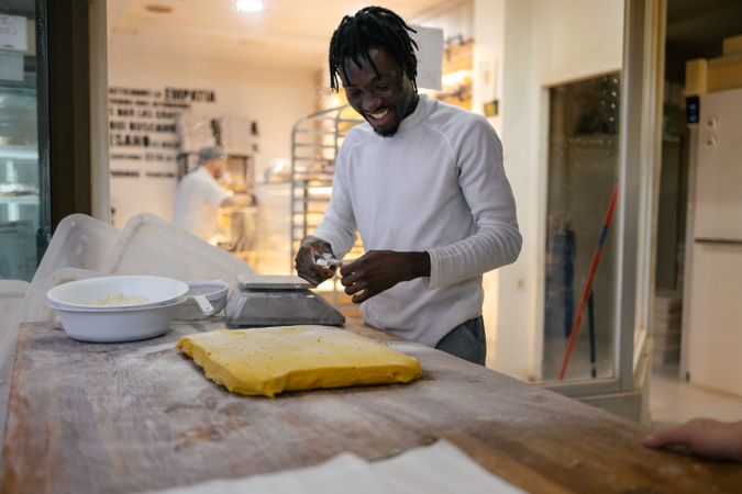 Black baker cutting dough with spatula