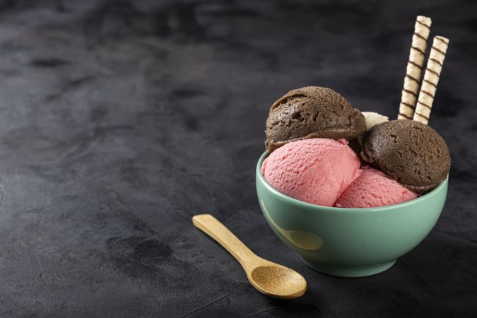 Bowl with Neapolitan ice cream on dark background.