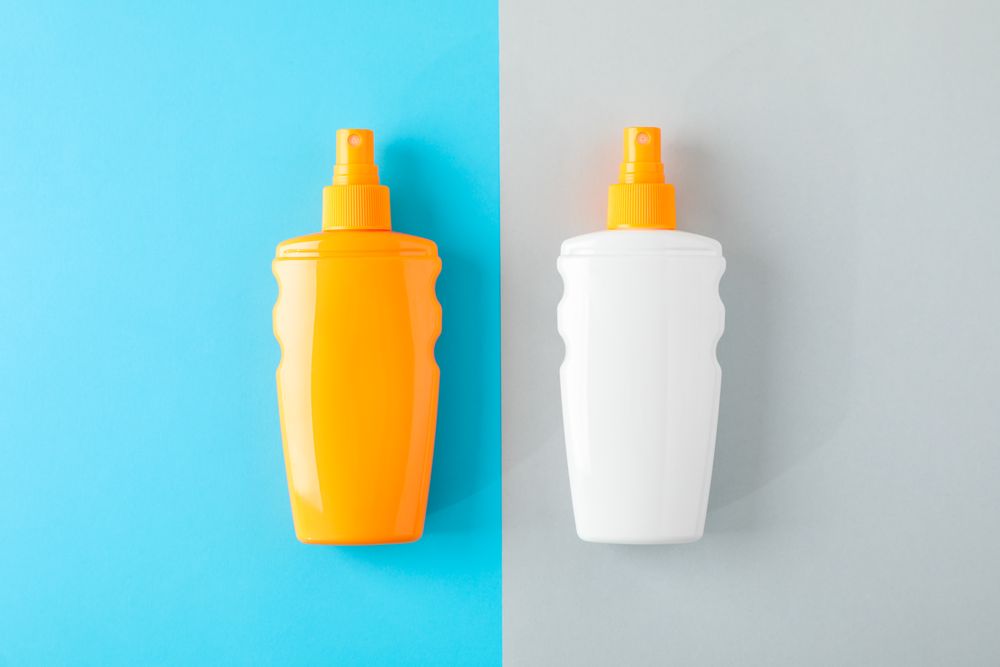 Composition with sunscreen sprays on two tone background. Space for text, top view