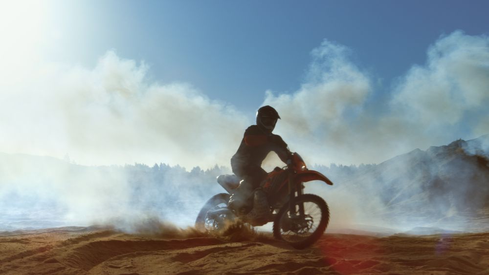 Professional Motocross FMX Motorcycle Rider Drives Through Smoke and Mist Over the Dirt Road Track.