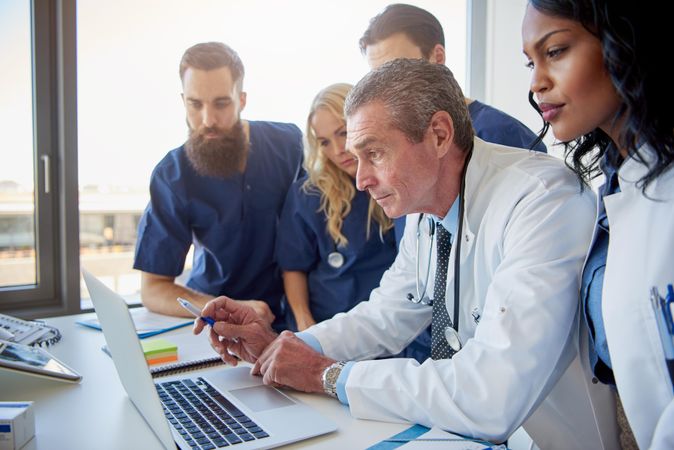 Diverse group of medical professionals working around a laptop