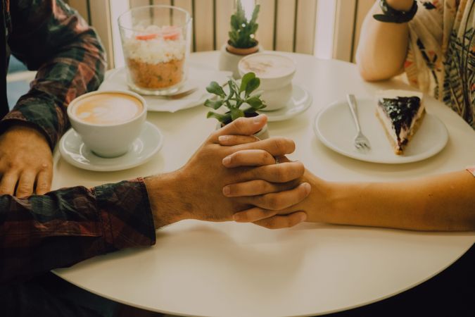 Anonymous loving couple having date in coffee shop