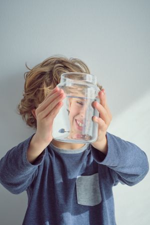 Smiling boy with glass jar of water