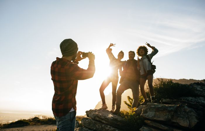 Young man taking photo of his friends with sun shining in the background