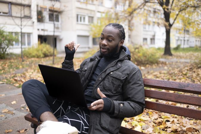 Young Black Man on Video Call Outdoors with Laptop in Park.