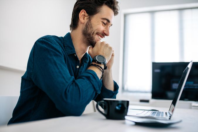 Software developer smiling and sitting in front of computer and working in office
