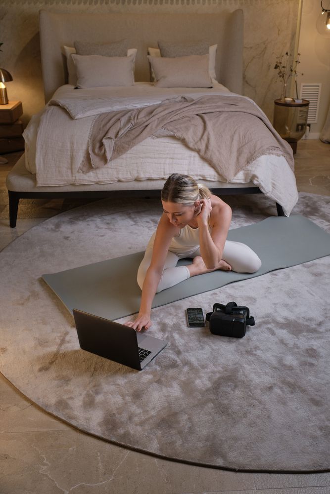 Woman in sportswear typing on laptop and doing yoga