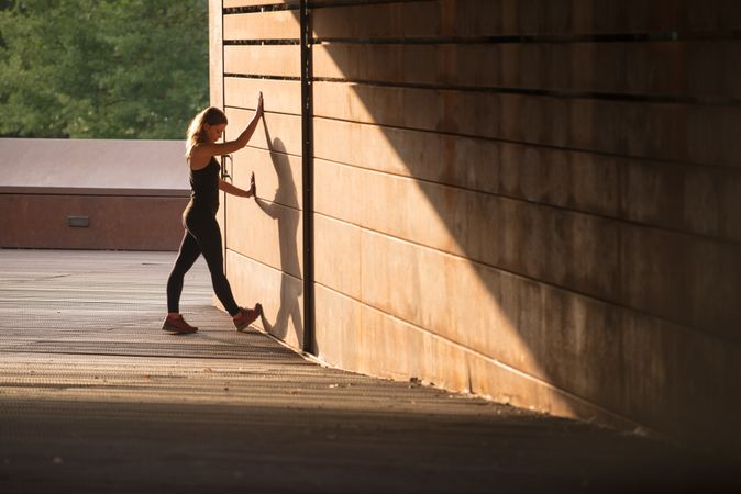 young woman stretching leaning in a street wall