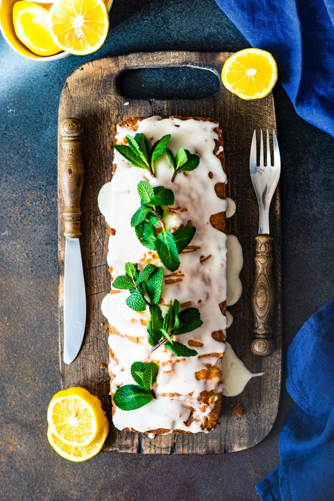 Tasty homemade lemon cake with fresh mint garnish on cutting board