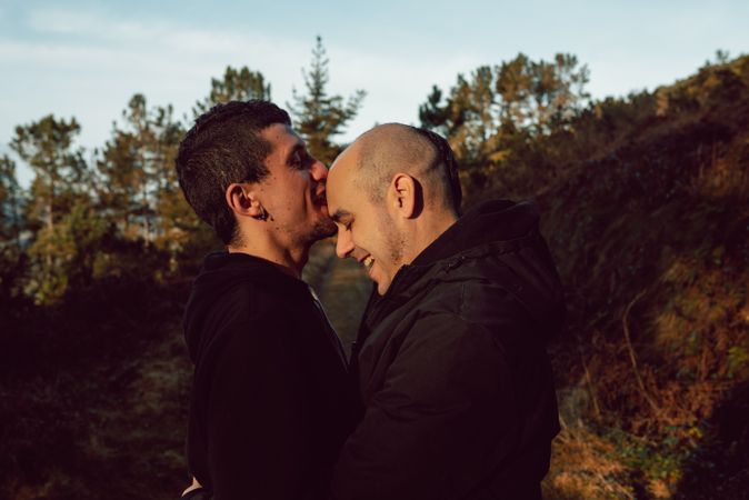 Smiling men hugging and kissing on countryside road