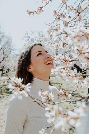 Young happy woman between trees in garden