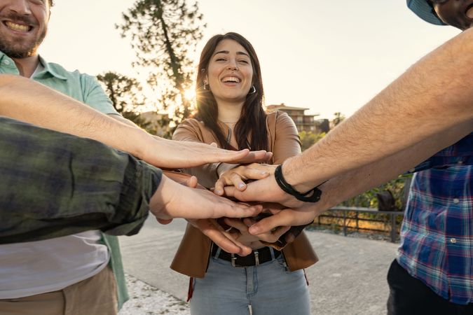 Diverse team putting their hands together in a circle around a smiling woman.