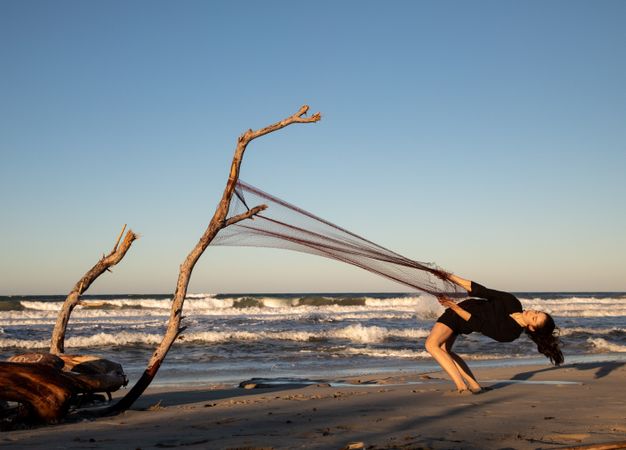 Woman in fishing net fixed on twig near water on shore