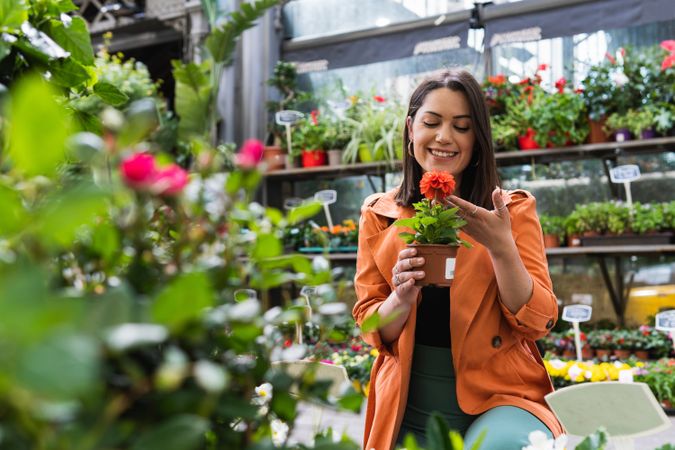 Smiling woman choosing potted flower in garden market