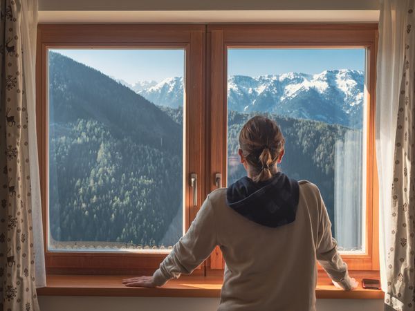 Anonymous woman looking at mountains from window
