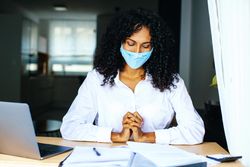 Content woman wearing a facemask reading over documents