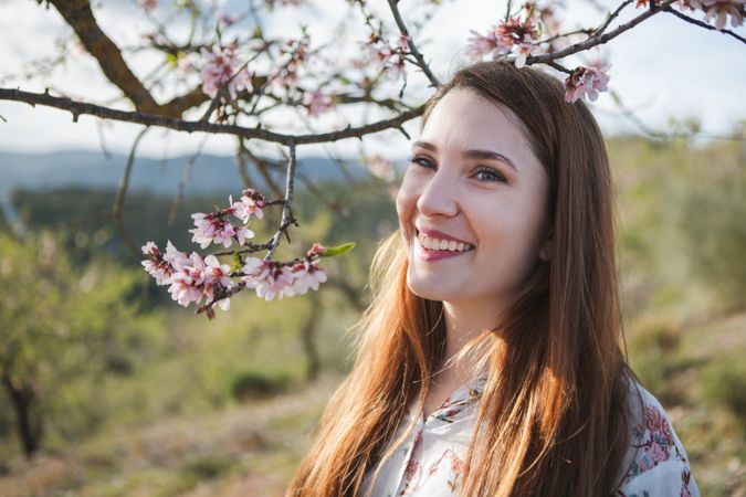 Young happy woman between trees in garden