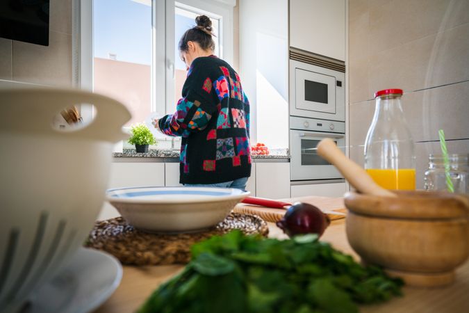 Crop woman washing tomato over sink