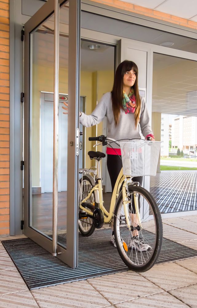 Woman with fixie bike opening a glass door to exit