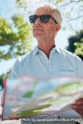 Close up shot of a mature man with a map standing outdoors in the city on a summer day 4dAmAb