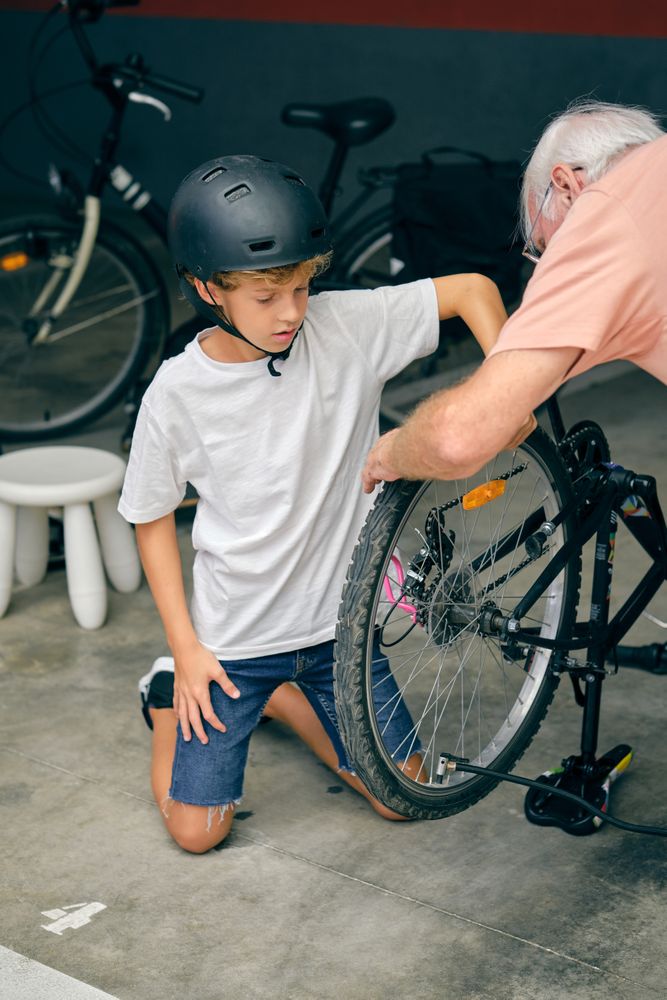 Concentrated boy inflating tire with grandfather