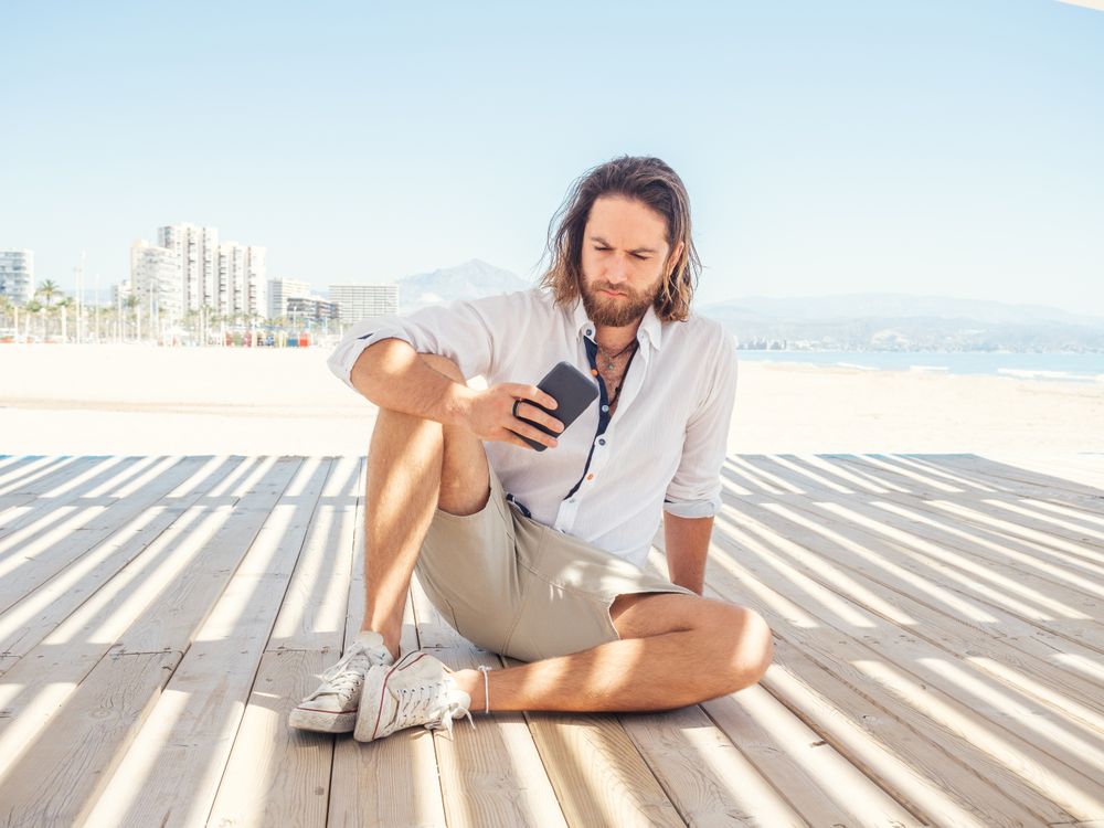 Man using smartphone on beach