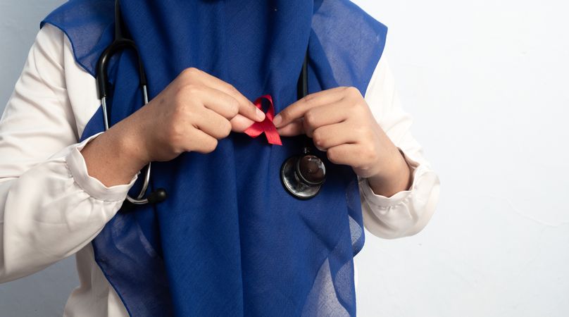 Close up Muslim Female Asian doctor or nurse wearing Red ribbons on cloth, HIV awareness concept, world AIDS day, world cancer day.