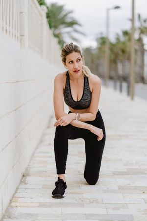 Satisfied sportswoman in active clothing smiling while exercising