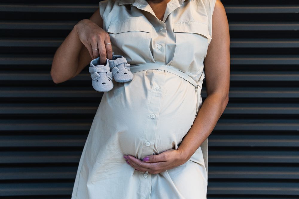 Anonymous Black woman showing baby booties