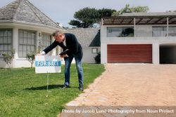 Real estate agent with for sale sign outside a new house 4d8qwE