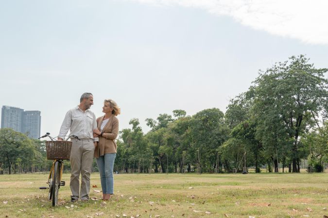 Older couple going for a stroll in the park with a bicycle