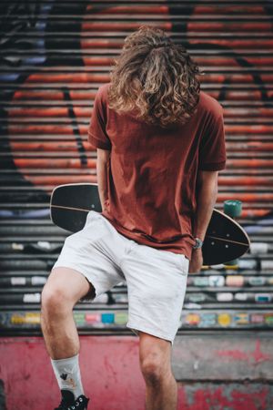 Content rider with longboard standing on urban street