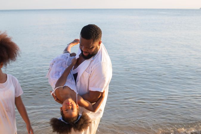 Father holding daughter upside down above the beach