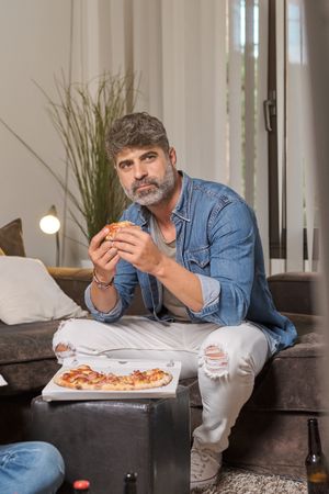 Mature man eating pizza at home